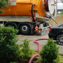Schlauch und orangefarbener Saugwagen für Rohrreinigung bei Mannheim